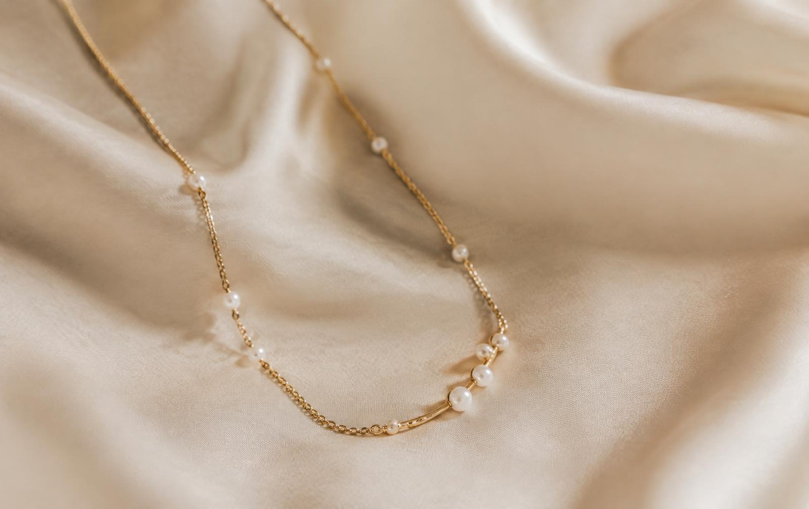 Gold necklace with pearls on cream silk